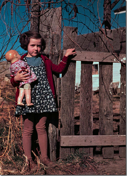 Girl with doll standing by fence Girl with doll standing by fence
