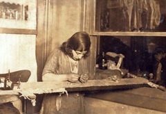 Tenement homework; a girl of 13 working at embroidery in a far corner of a dimly lighted room. 