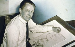 Charles Schulz, half-length portrait, facing front, seated at drawing table with drawing of Charlie Brown (1956).