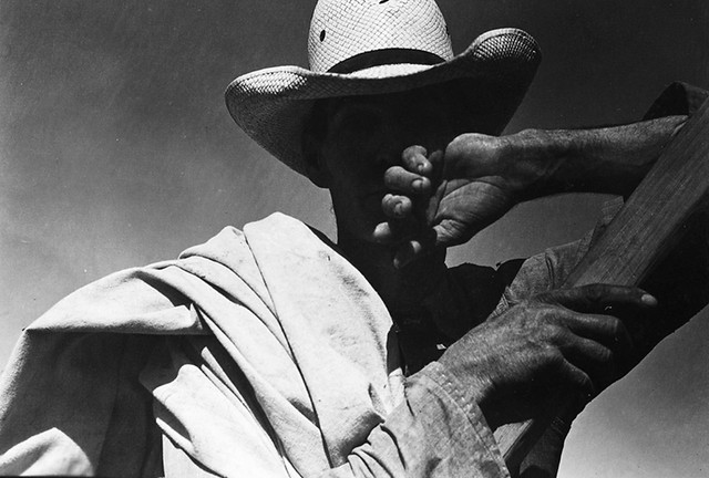 Migratory cotton picker with his sack slung over his shoulder rests at the scales before returning to work in the field
