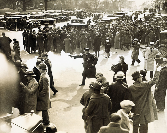 A police officer fires a tear gas pistol at demonstrators at the edge of the U.S. Capitol grounds December 1, 1930.